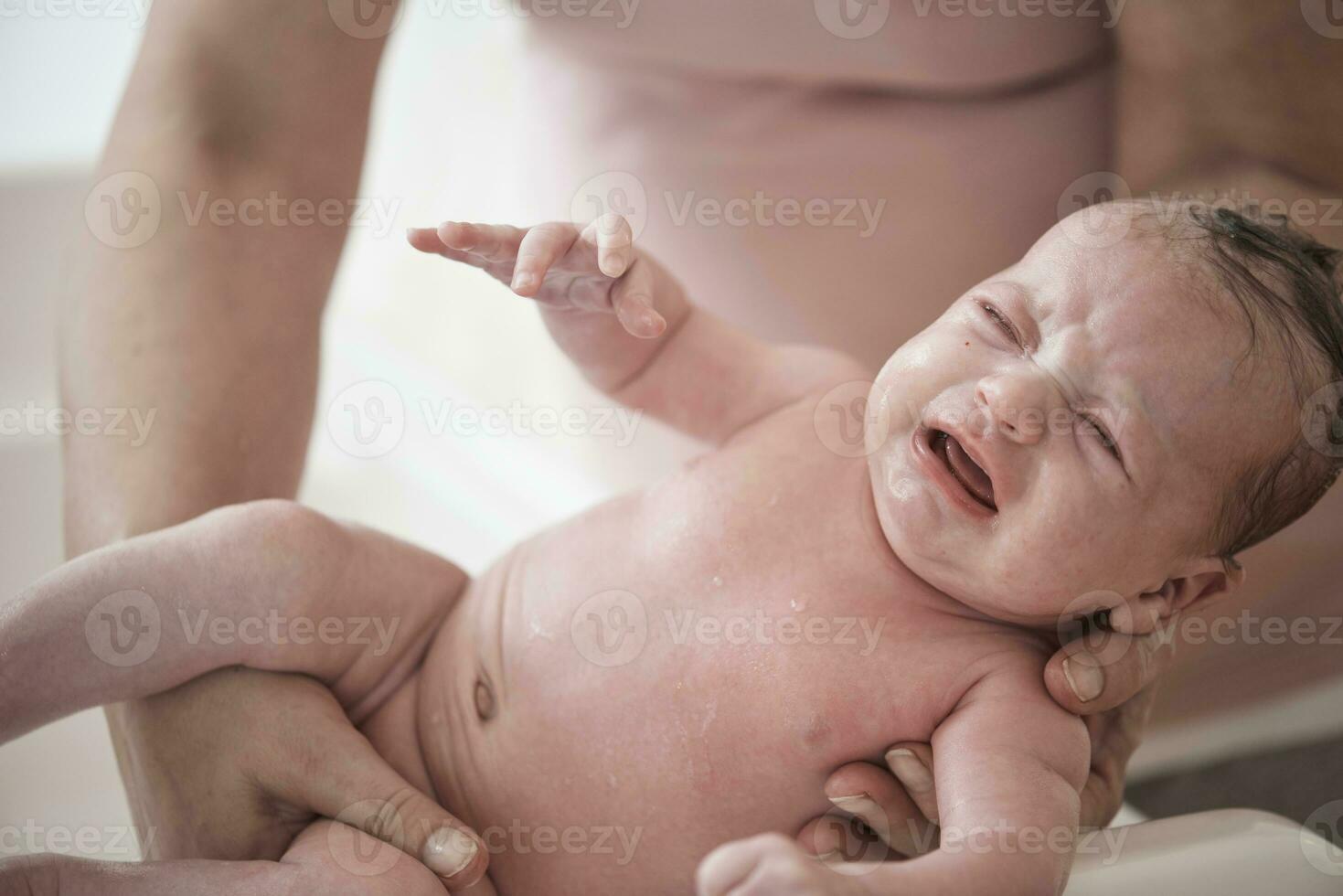 Newborn baby girl taking a  bath photo