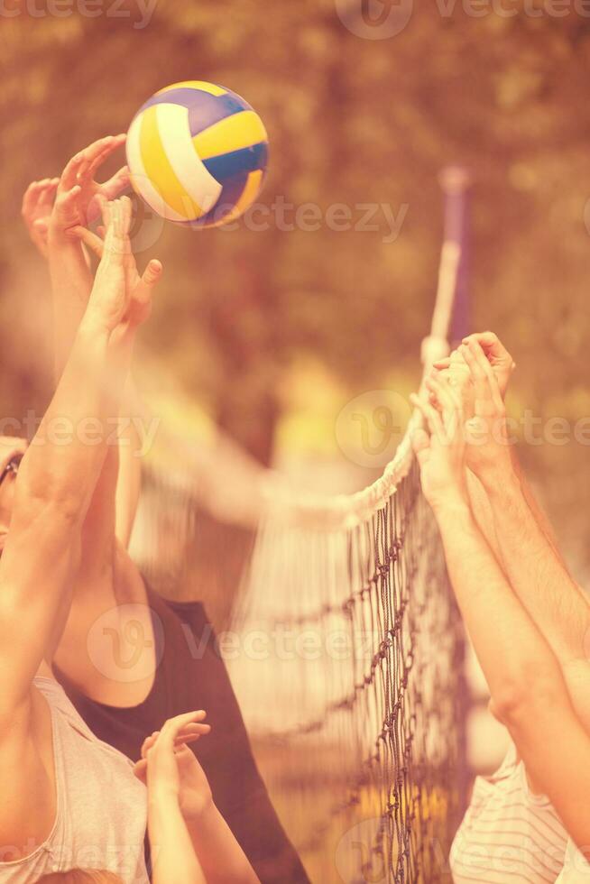 grupo de jóvenes amigos jugando voleibol de playa foto