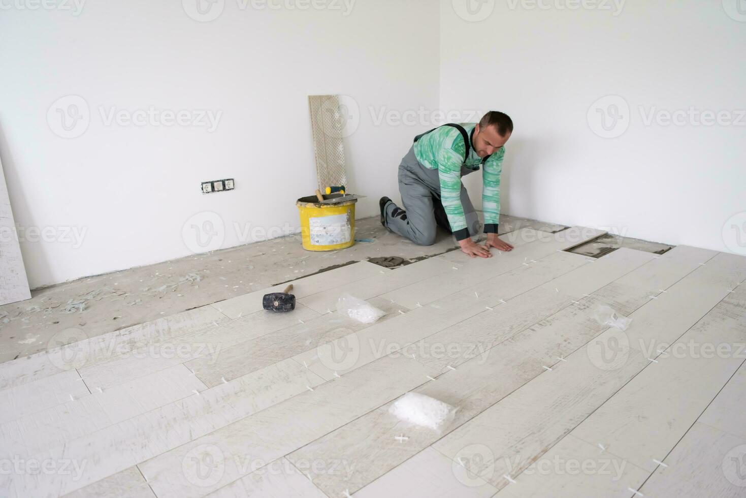 worker installing the ceramic wood effect tiles on the floor photo
