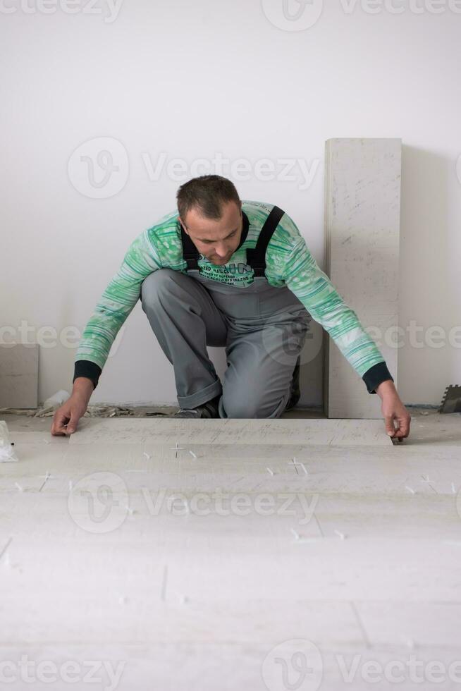 worker installing the ceramic wood effect tiles on the floor photo