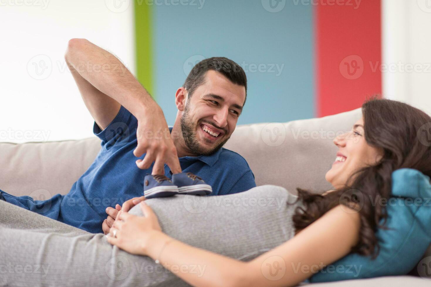 young pregnant couple relaxing on sofa photo