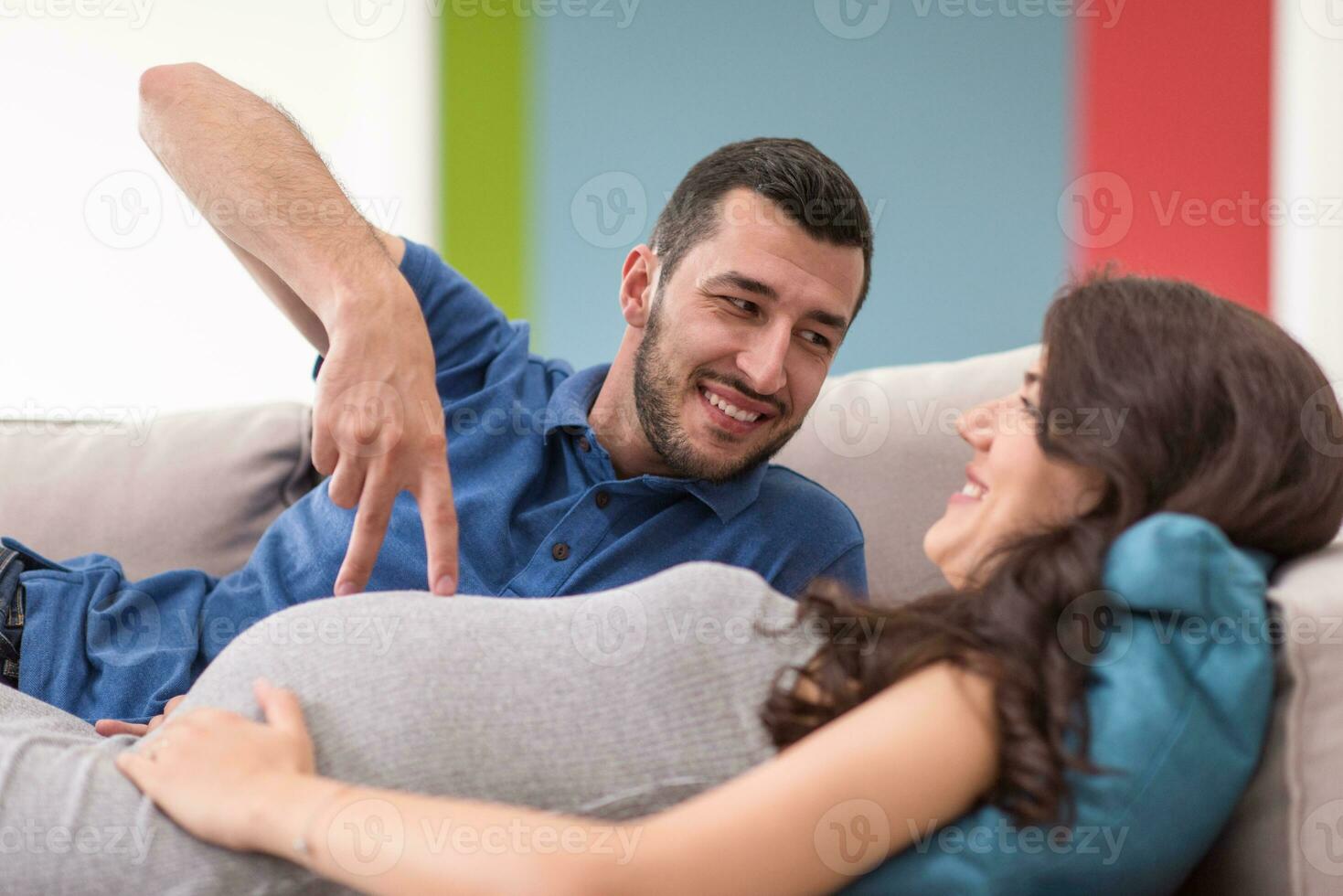 young pregnant couple relaxing on sofa photo