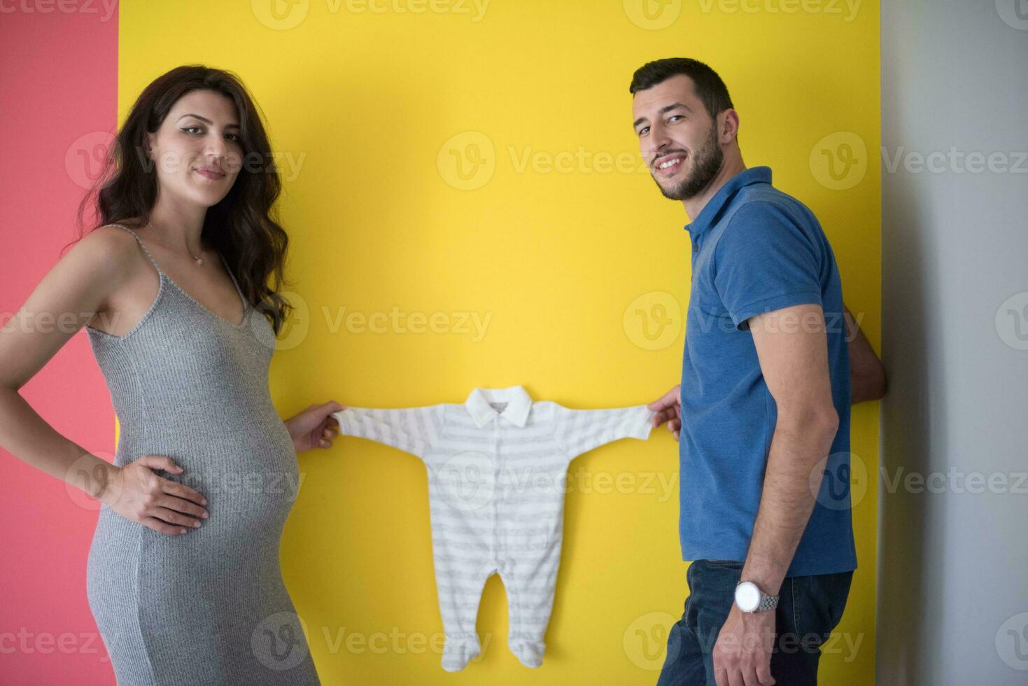 young couple holding baby bodysuits photo