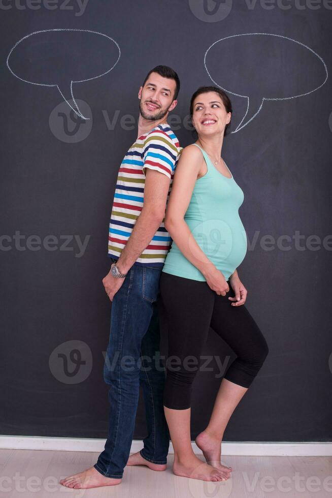 pregnant couple writing on a black chalkboard photo