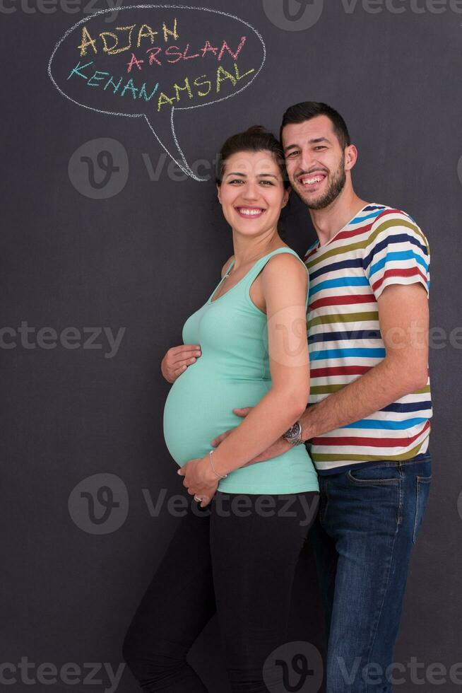 pregnant couple writing on a black chalkboard photo