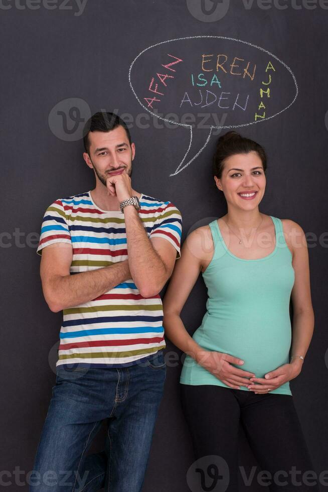 pregnant couple writing on a black chalkboard photo