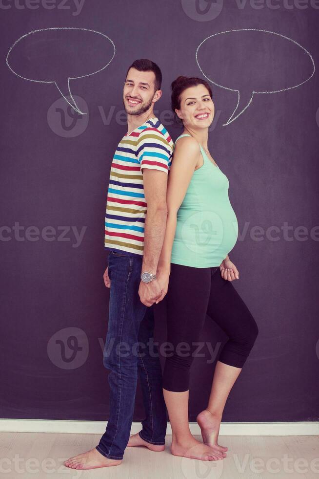 pregnant couple writing on a black chalkboard photo