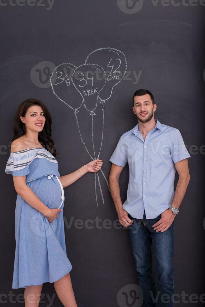 pregnant couple drawing their imaginations on chalk board photo