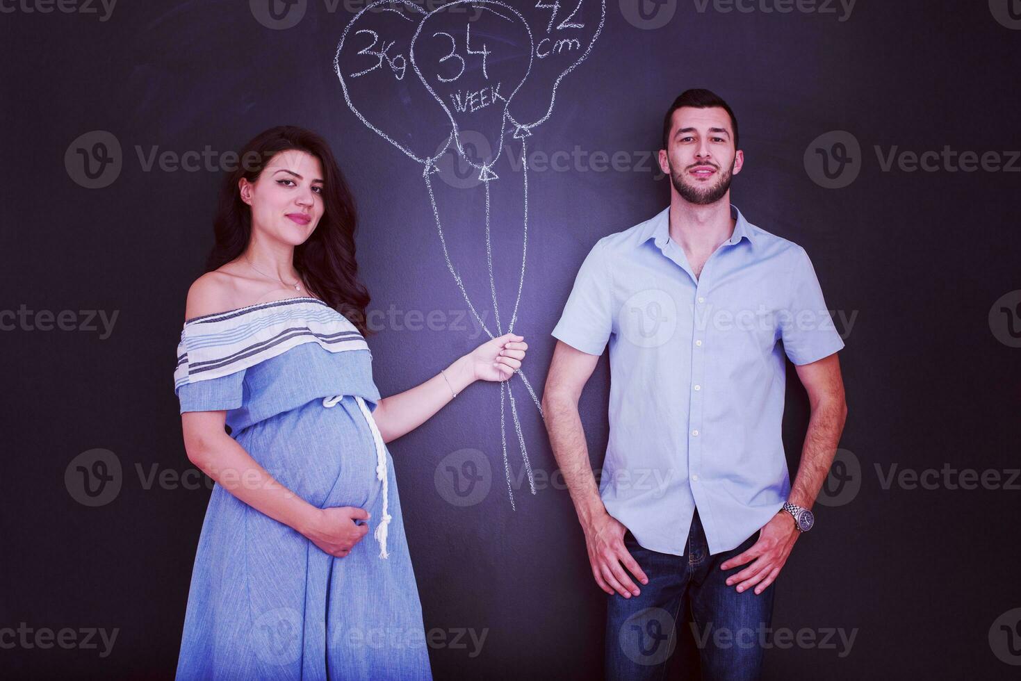 pregnant couple drawing their imaginations on chalk board photo