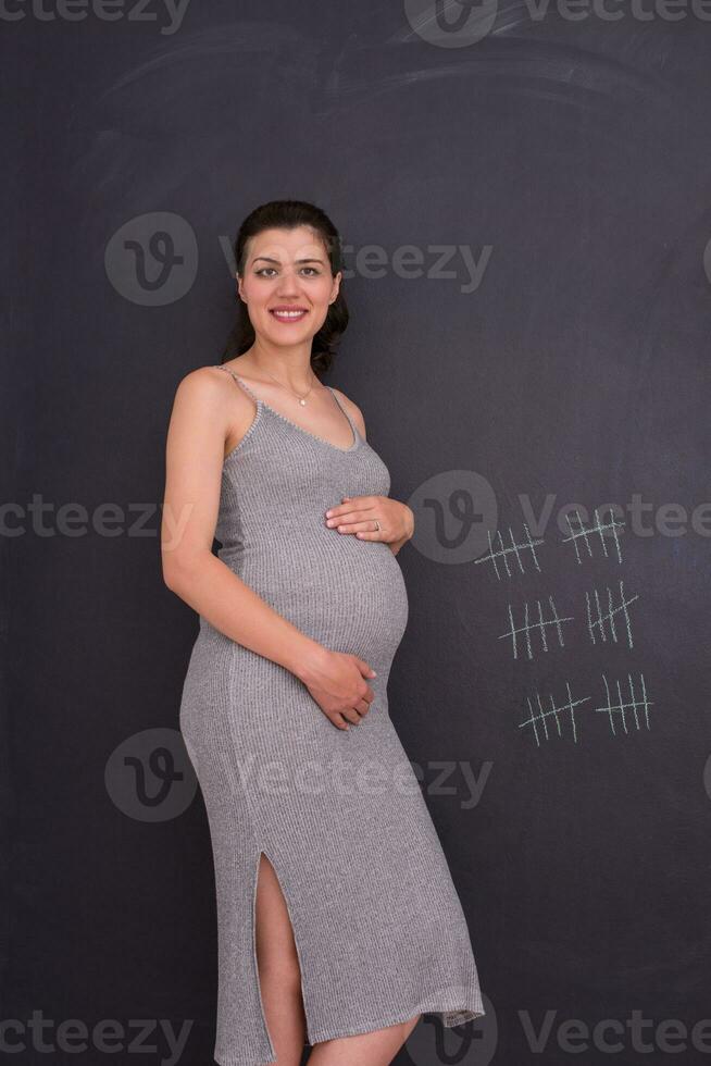 Portrait of pregnant woman in front of black chalkboard photo