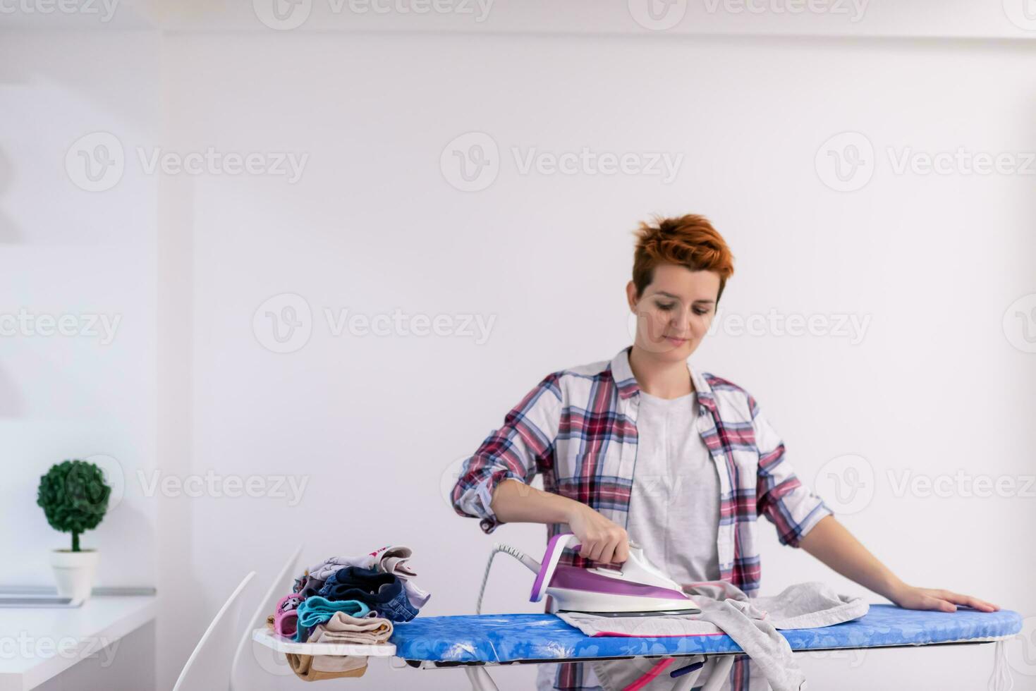 mujer pelirroja planchando ropa en casa foto