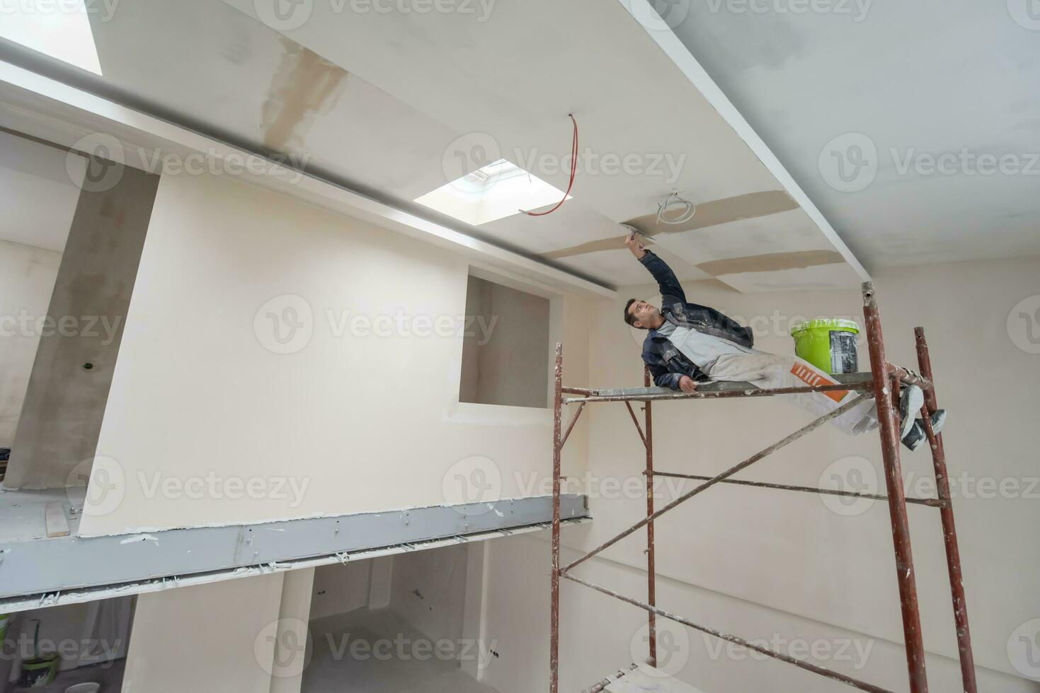 trabajador de la construcción enyesado en el techo de yeso foto