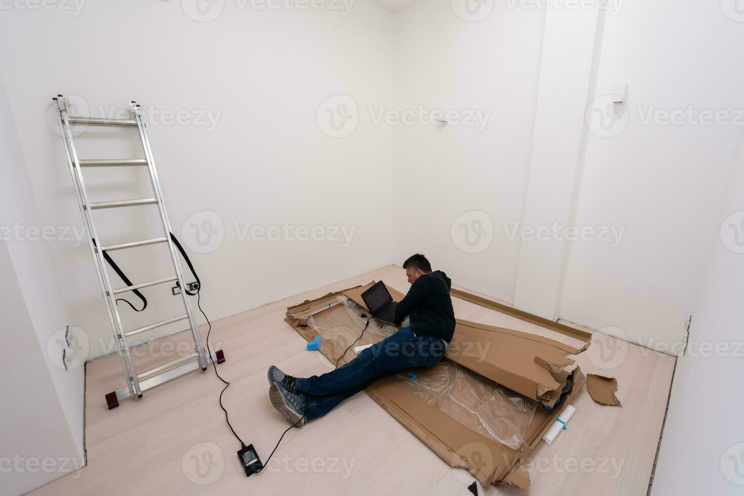 man using laptop while lying on cardboard box photo