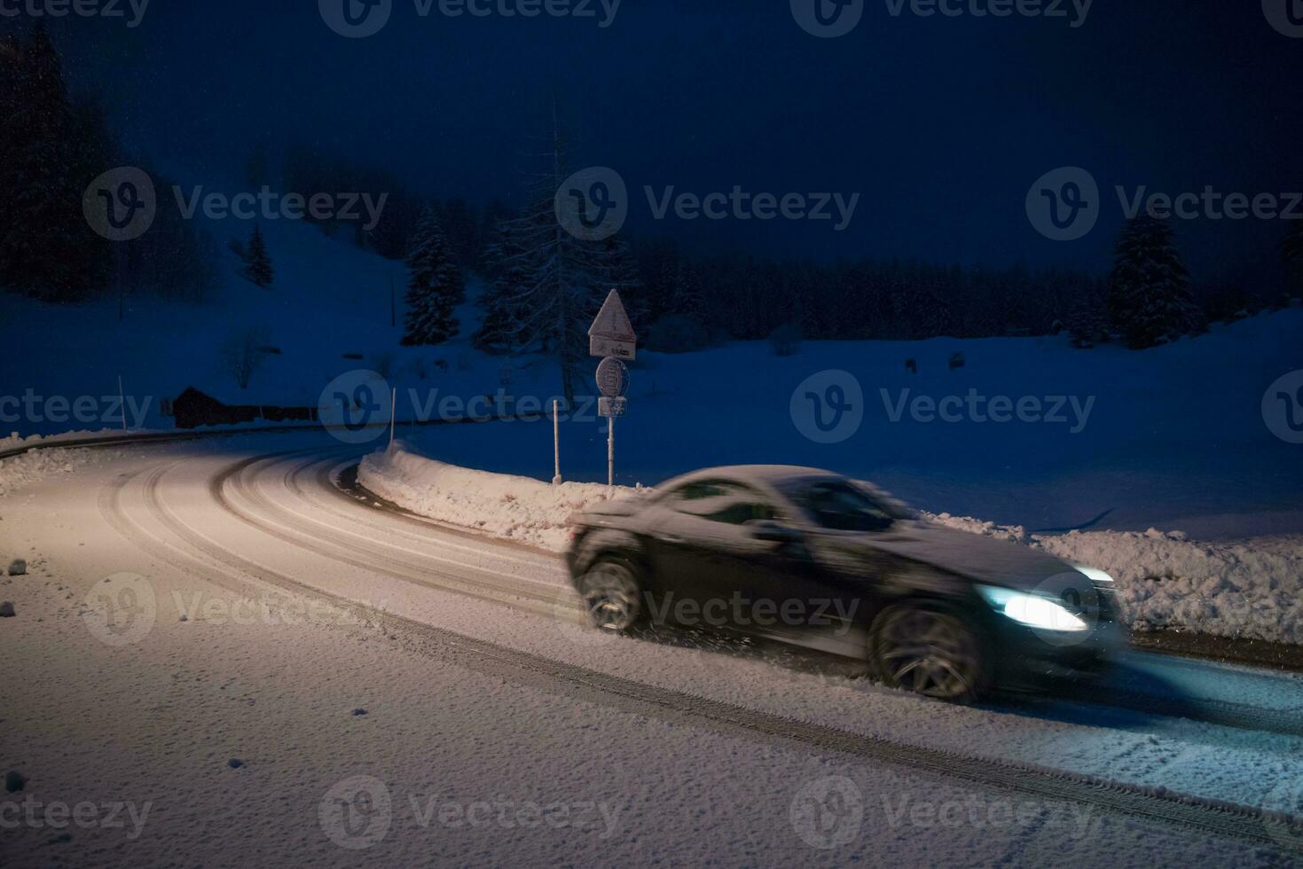 car driving on dangerous road at night on snow photo