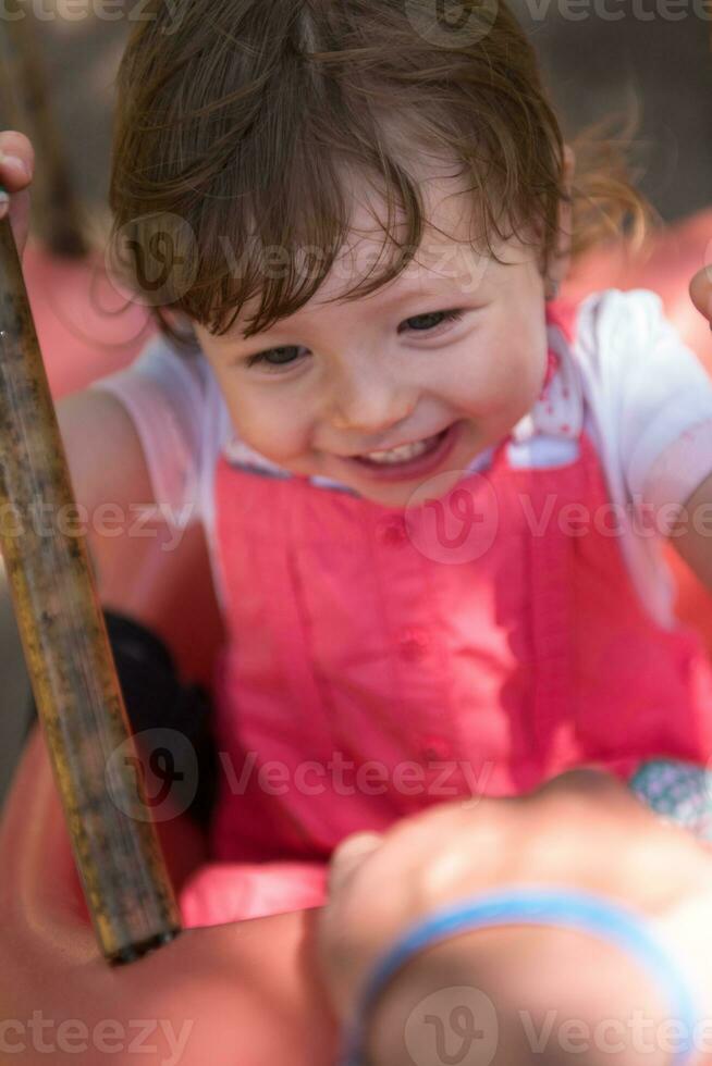 little girl swinging  on a playground photo