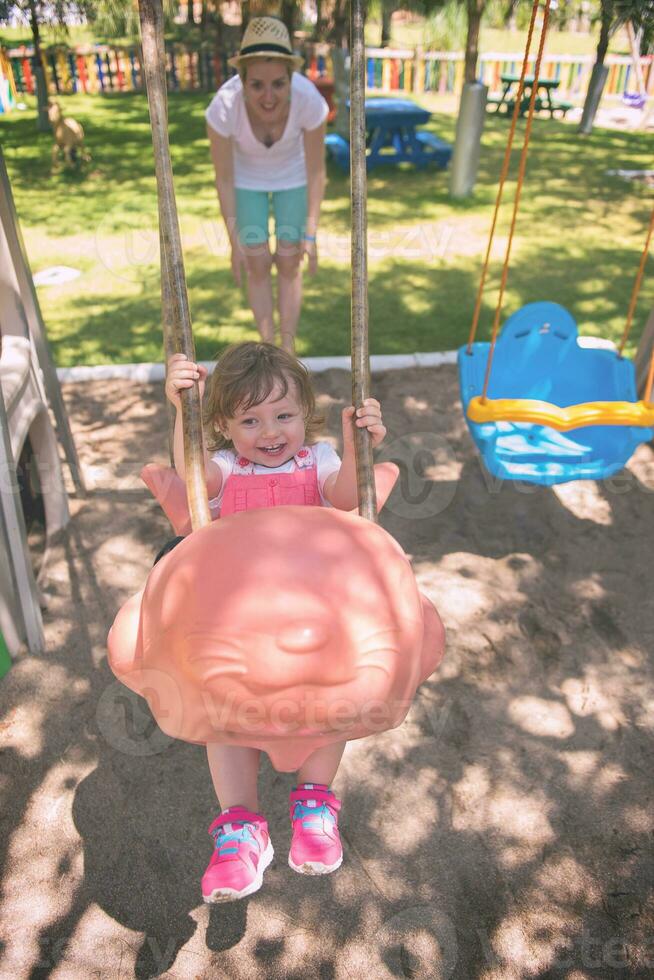 mother and daughter swinging in the park photo