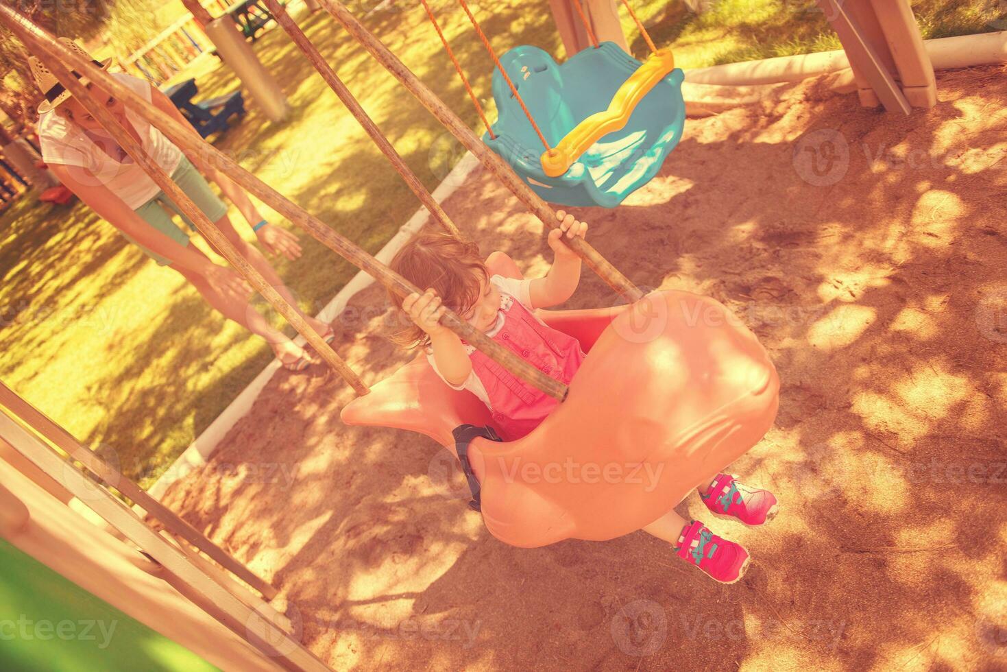 mother and daughter swinging in the park photo