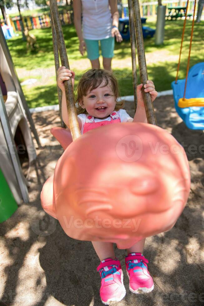mother and daughter swinging in the park photo
