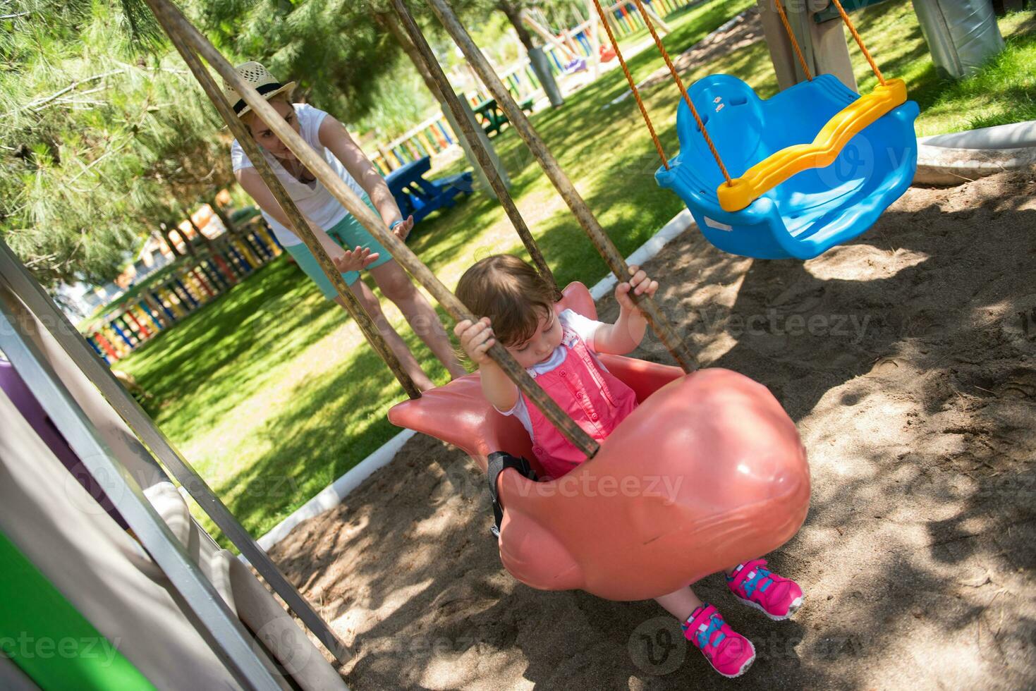 mother and daughter swinging in the park photo