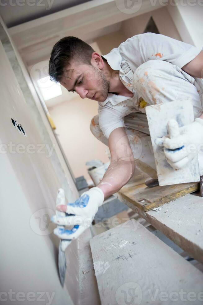 construction worker plastering on gypsum walls photo