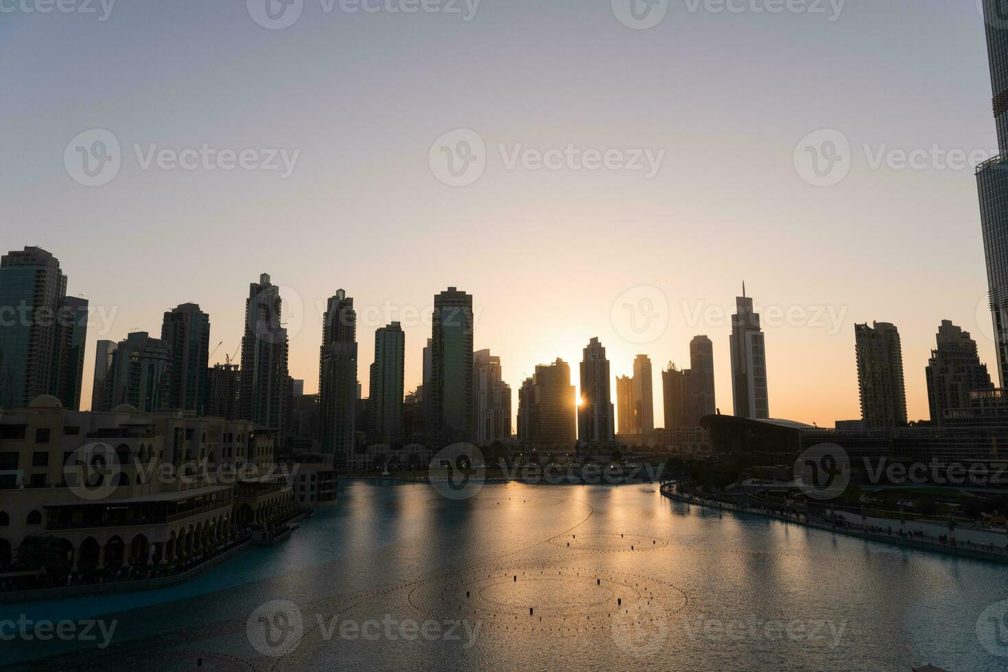 Dubai singing fountains at night lake view between skyscrapers. City skyline in dusk modern architecture in UAE capital downtown. photo