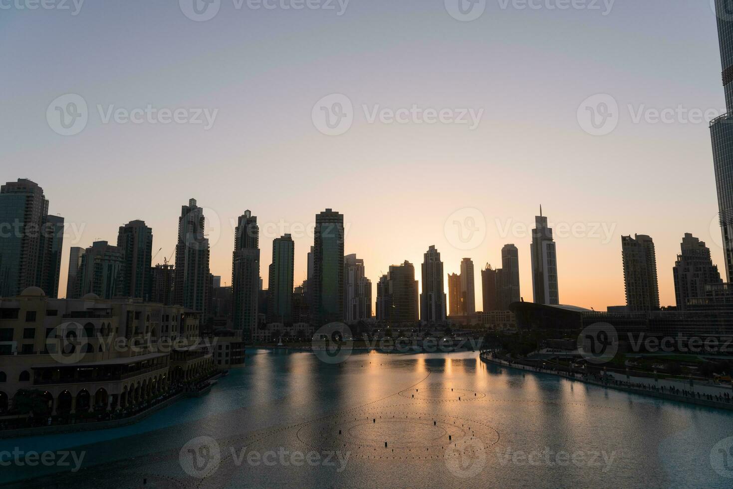 Dubai singing fountains at night lake view between skyscrapers. City skyline in dusk modern architecture in UAE capital downtown. photo