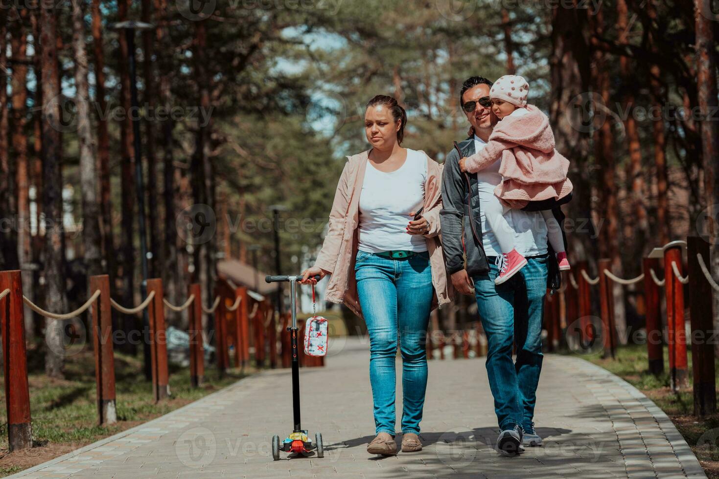 Family fun in the park. Happy family spending time in park and playing with their daughter photo