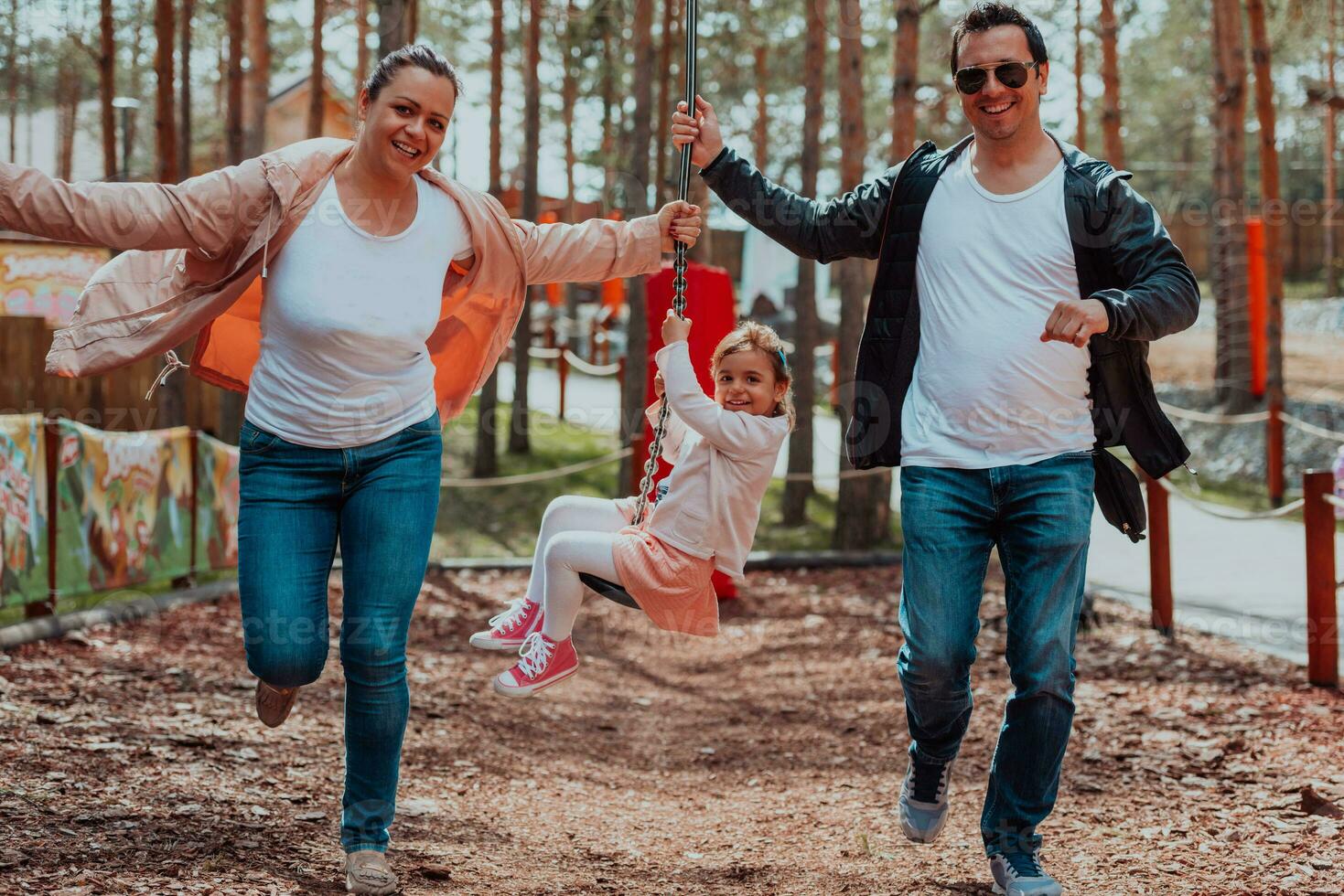 Family fun in the park. Happy family spending time in park and playing with their daughter photo