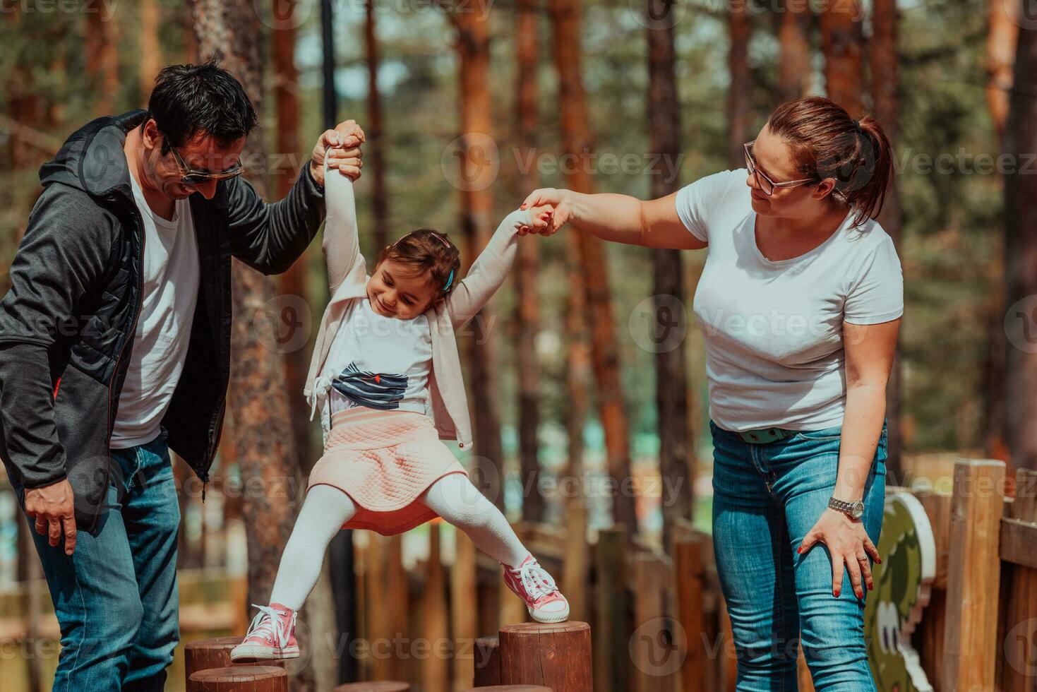 Family fun in the park. Happy family spending time in park and playing with their daughter photo