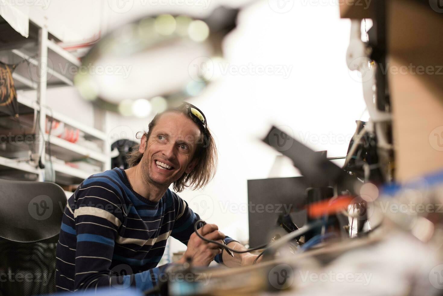 Industrial worker man soldering cables of manufacturing equipment in a factory. Selective focus photo