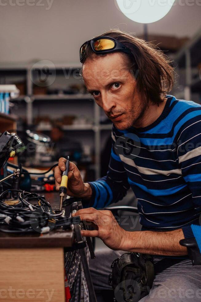 Industrial worker man soldering cables of manufacturing equipment in a factory. Selective focus photo