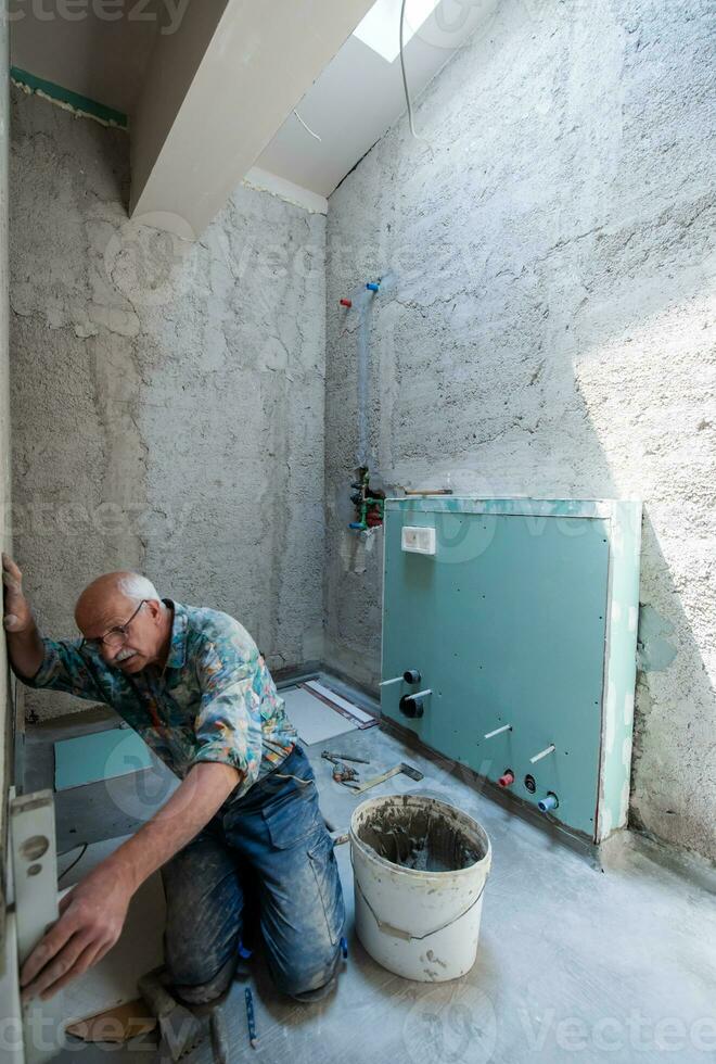 trabajador utilizando nivel herramienta mientras instalando grande cerámico losas foto