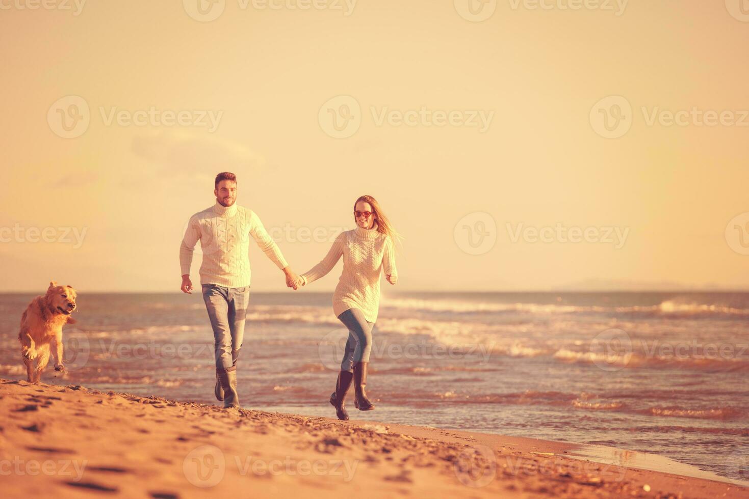 couple with dog having fun on beach on autmun day photo