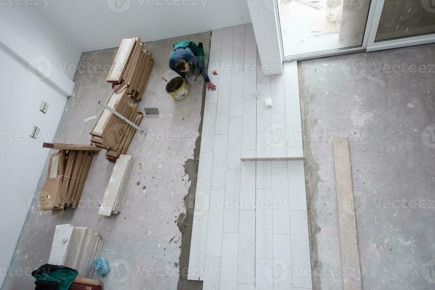 worker installing the ceramic wood effect tiles on the floor photo