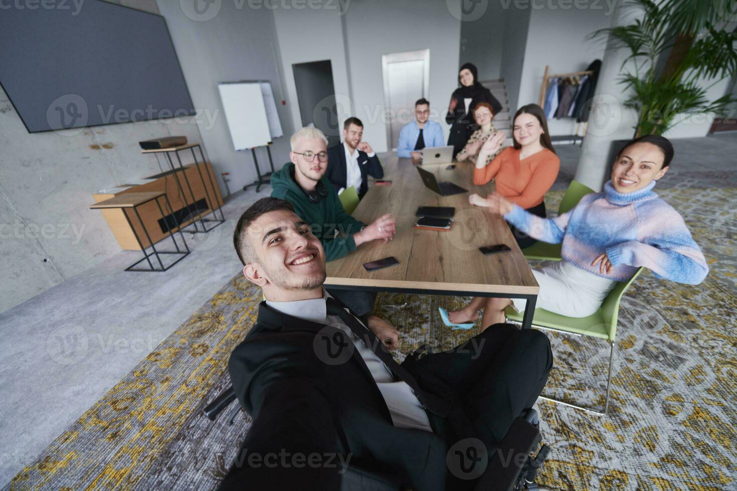 In a modern office, a group of businessmen gathers around a table during a meeting, capturing a moment of camaraderie and teamwork as they take a selfie photo