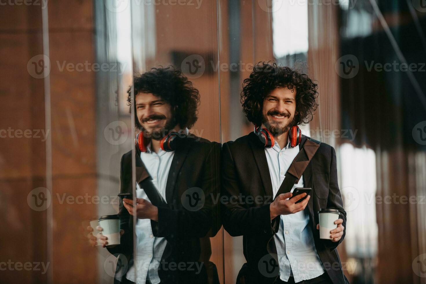 Trendy businessman with leather briefcase in financial district using smartphone while listening audio songs headphones drinking coffee photo