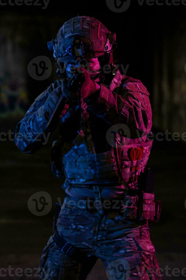 Ejército soldado en combate uniformes con un asalto rifle y combate casco noche misión oscuro antecedentes. azul y púrpura gel ligero efecto. foto