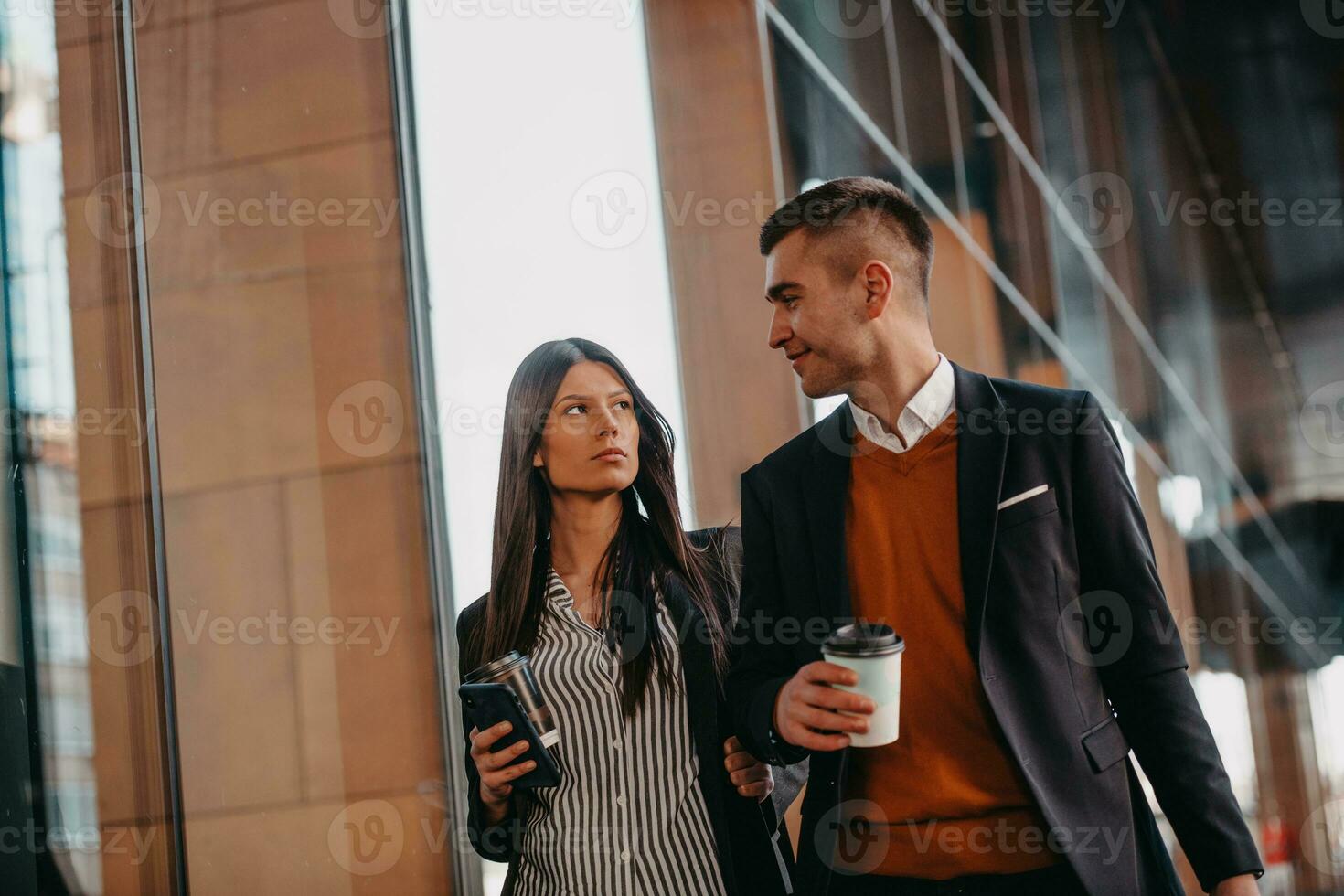 Business man and business woman talking and holding luggage traveling on a business trip, carrying fresh coffee in their hands.Business concept photo