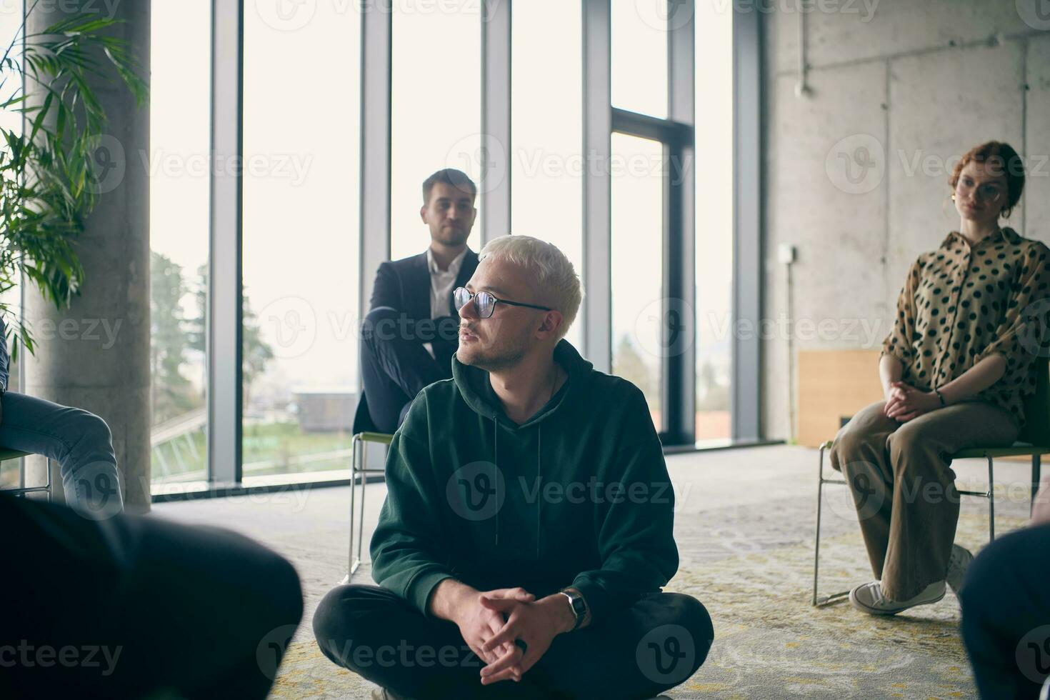 A young businessman sitting at the center of a circle, passionately sharing his business ideas with his colleagues, fostering an atmosphere of collaboration and innovation in a dynamic and engaging workplace photo