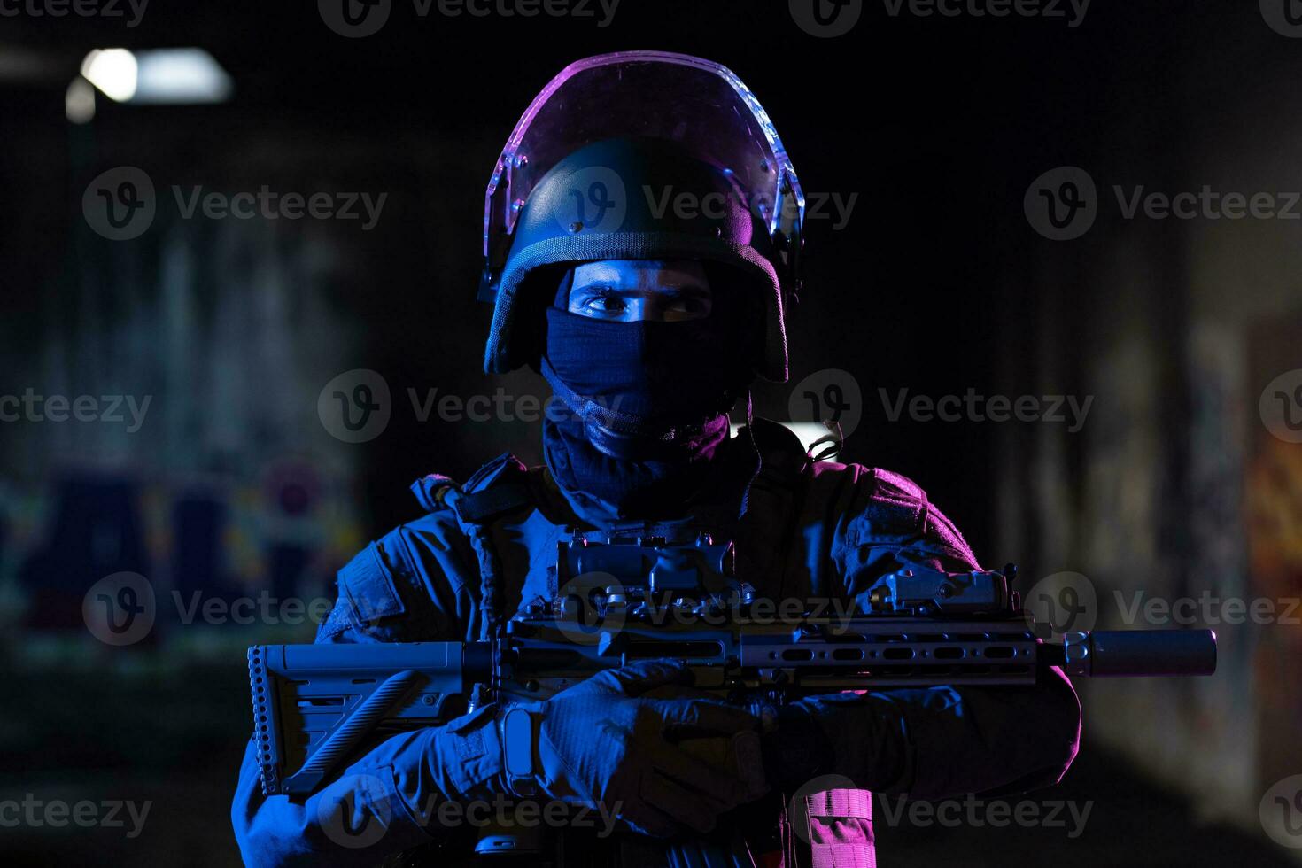 Army soldier in Combat Uniforms with an assault rifle and combat helmet night mission dark background. Blue and purple gel light effect. photo