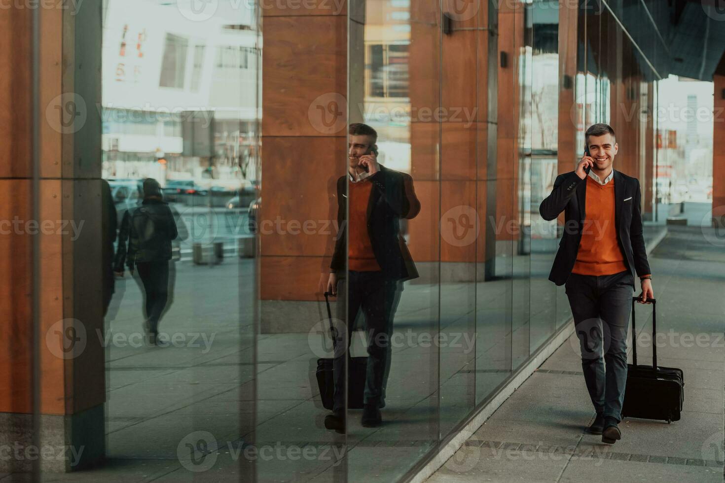Going to airport terminal. Confident businessman traveler walking on city streets and pulling his suitcase drinking coffee and speaking on smartphone photo