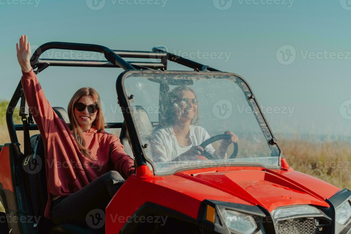 Two young happy excited women enjoying beautiful sunny day while driving a off road buggy car on mountain nature photo