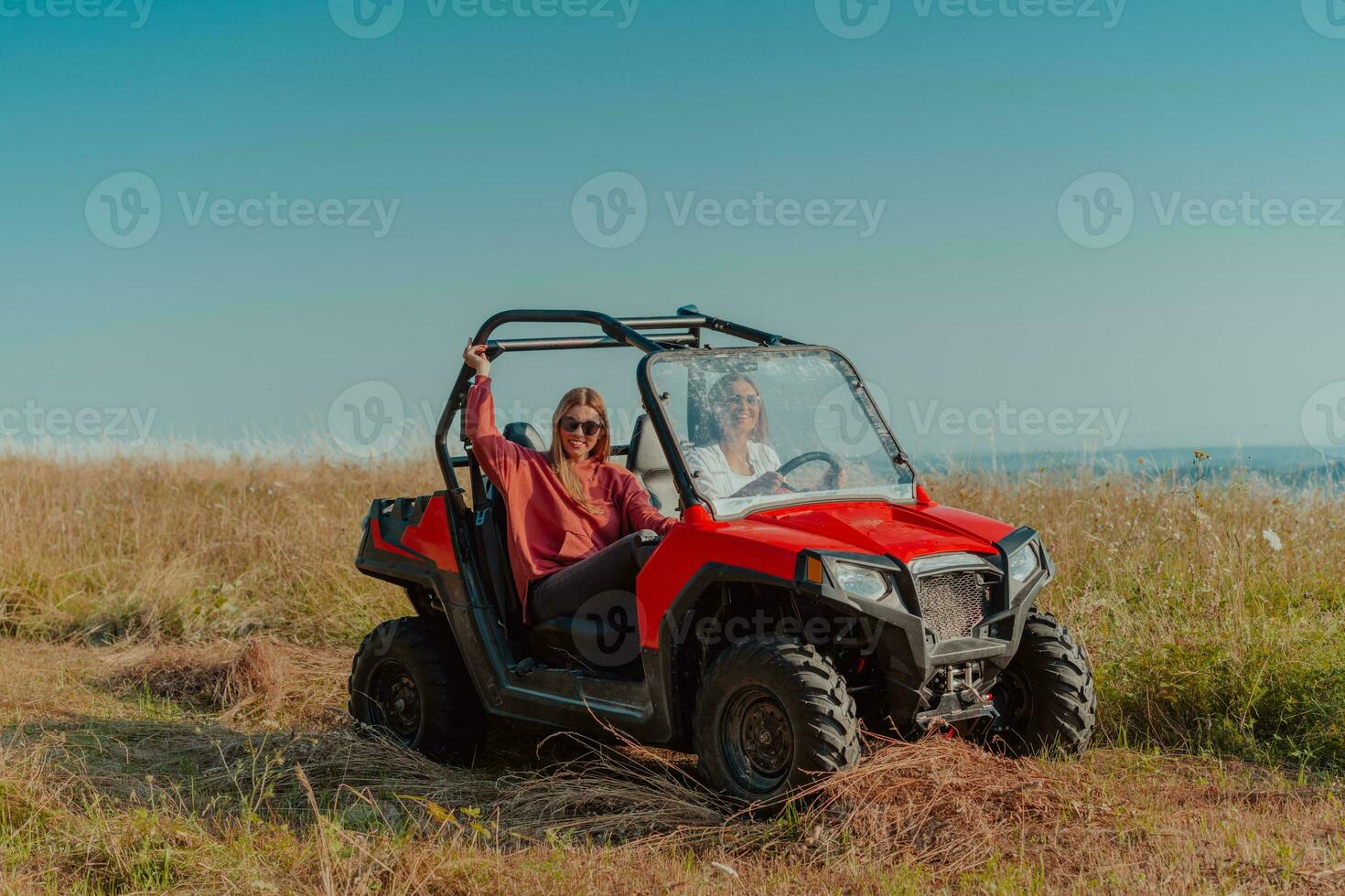 Two young happy excited women enjoying beautiful sunny day while driving a off road buggy car on mountain nature photo