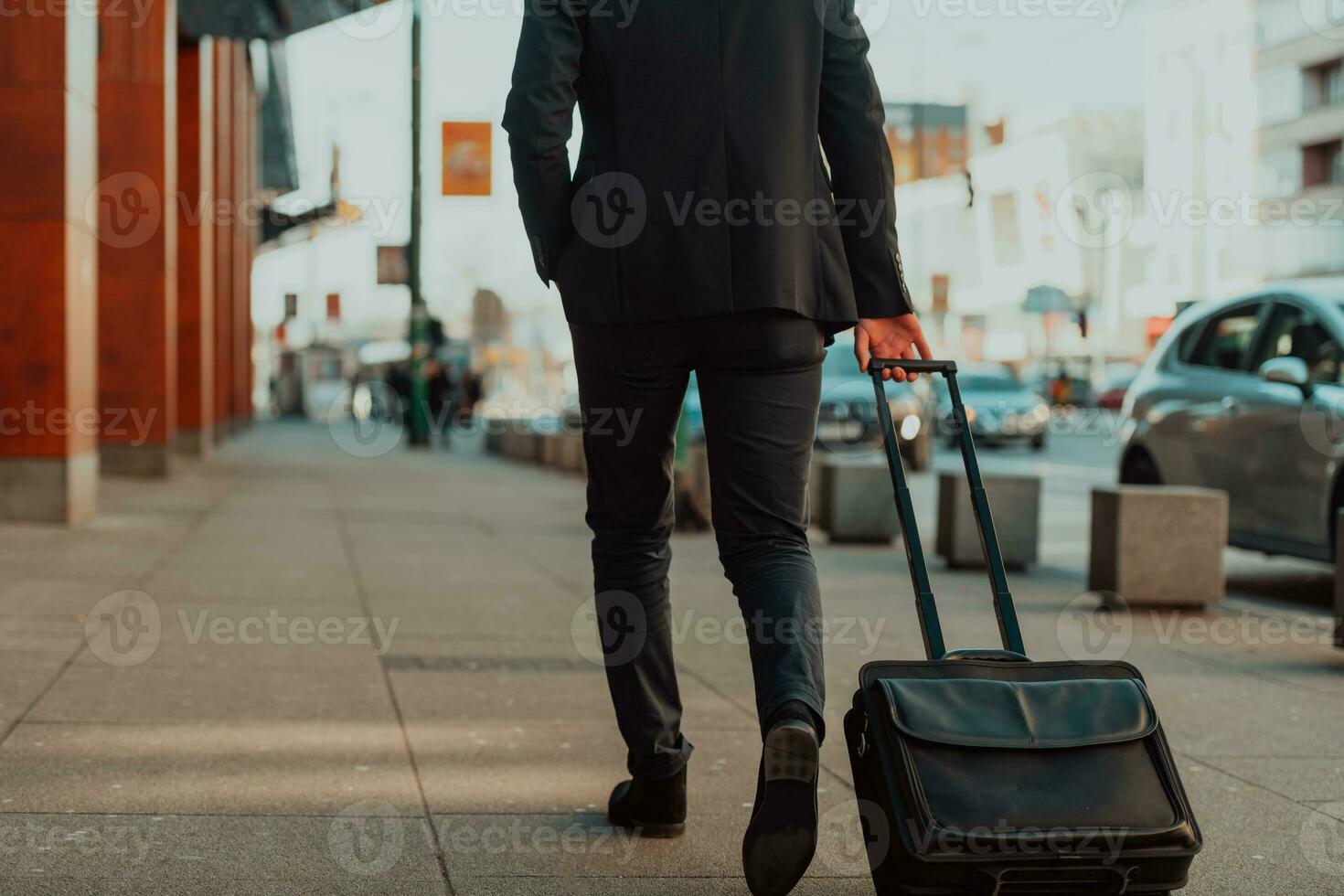 Going to airport terminal. Confident businessman traveler walking on city streets and pulling his suitcase drinking coffee and speaking on smartphone photo