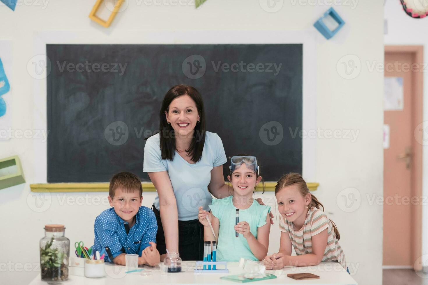 Elementary School Science Classroom Enthusiastic Teacher Explains Chemistry to Diverse Group of Children, Little Boy Mixes Chemicals in Beakers. Children Learn with Interest photo