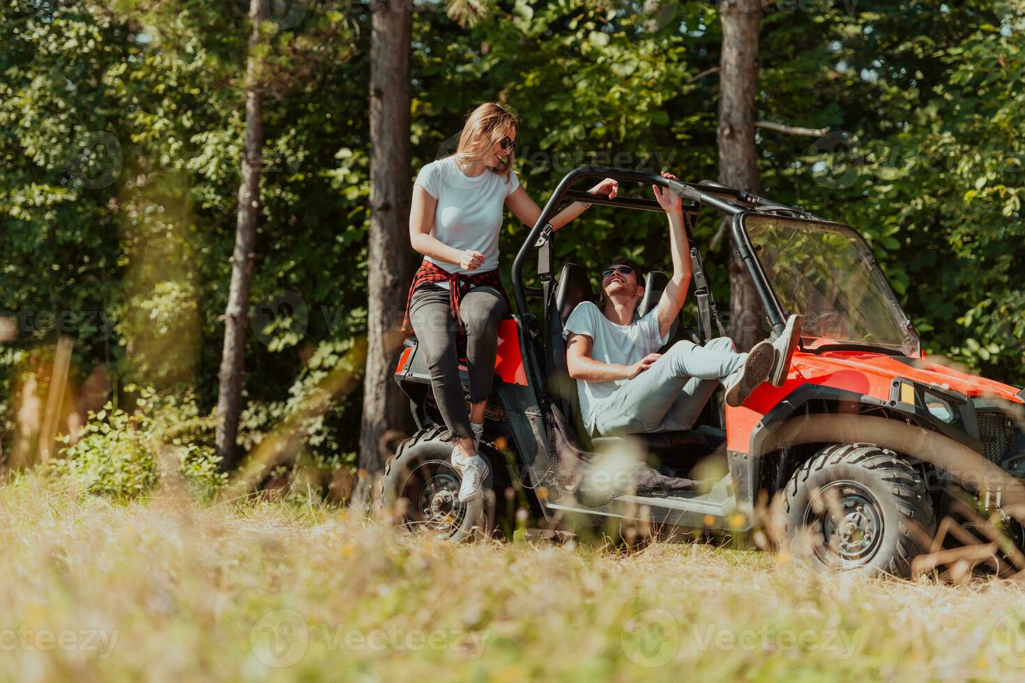 Young happy excited couple enjoying beautiful sunny day while driving a off road buggy car on mountain nature photo