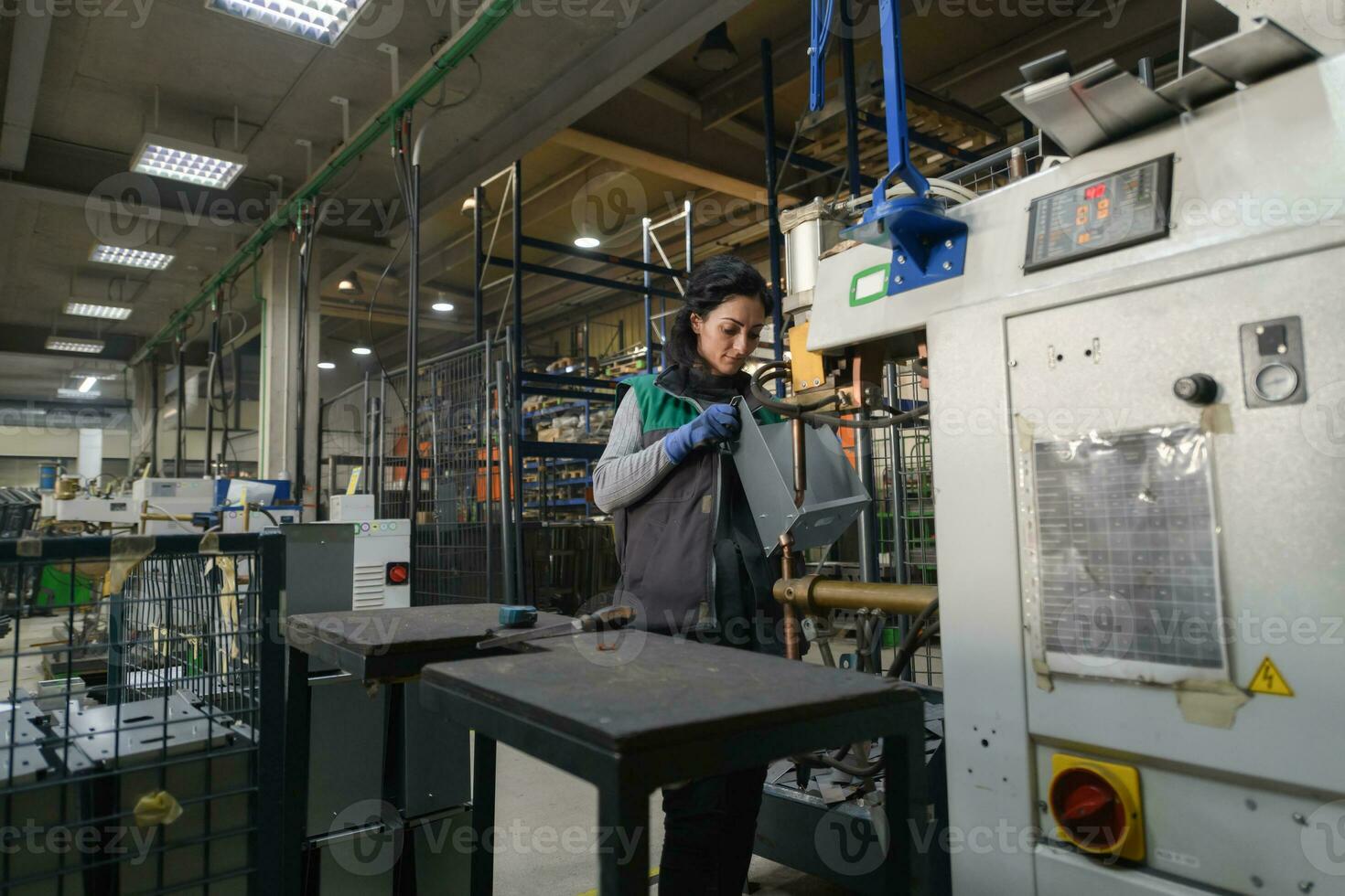 a woman working in a modern metal factory assembles parts for a new machine photo