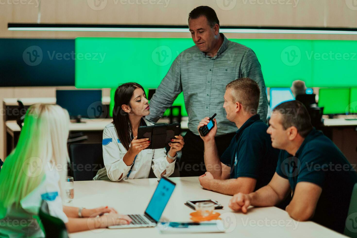 Group of security guards sitting and having briefing In the system control room They're working in security data center surrounded by multiple Screens photo