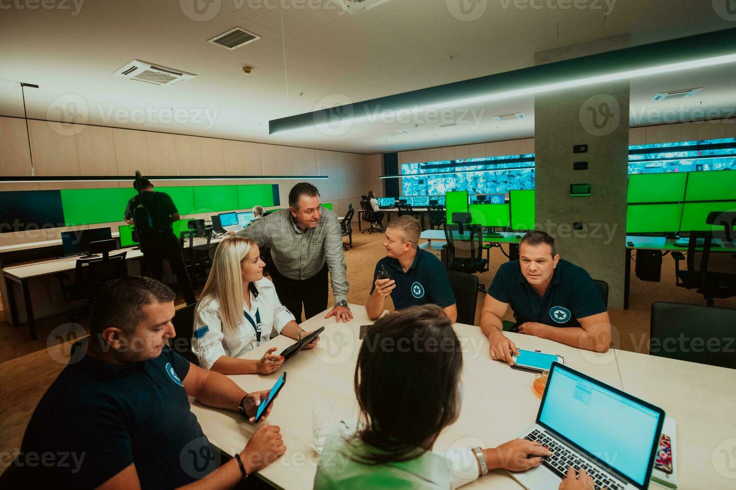 Group of security guards sitting and having briefing In the system control room They're working in security data center surrounded by multiple Screens photo