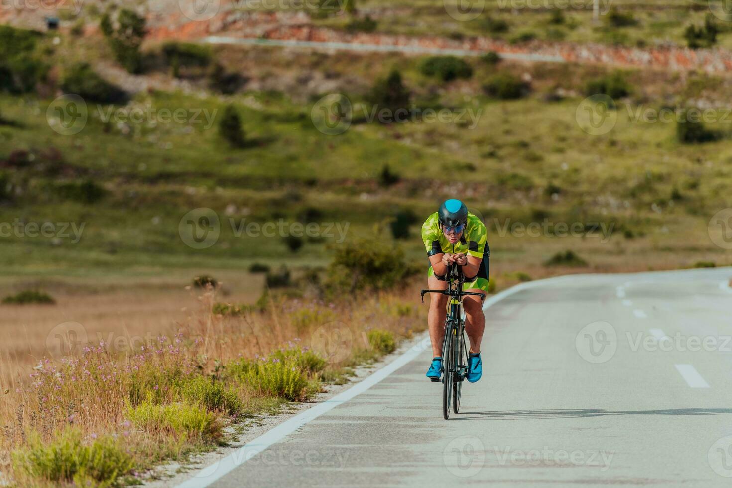 lleno longitud retrato de un activo triatleta en ropa de deporte y con un protector casco montando un bicicleta. selectivo atención foto